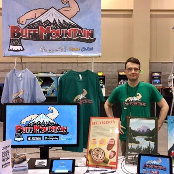 A photo of Tyler at a convention booth for his game Buff Mountain